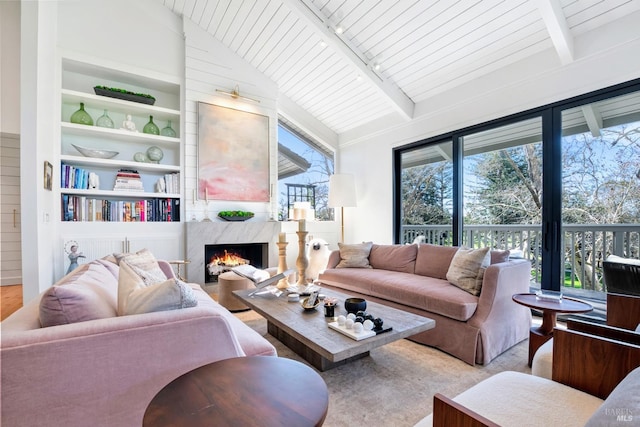 living room featuring built in shelves, lofted ceiling with beams, wood finished floors, a high end fireplace, and wood ceiling