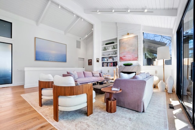 living area featuring built in shelves, wood finished floors, visible vents, high vaulted ceiling, and beam ceiling