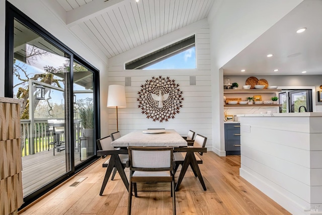 dining room with vaulted ceiling, light wood-style floors, visible vents, and a wealth of natural light