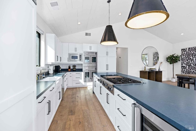 kitchen with beverage cooler, vaulted ceiling, white cabinets, appliances with stainless steel finishes, and light wood-type flooring