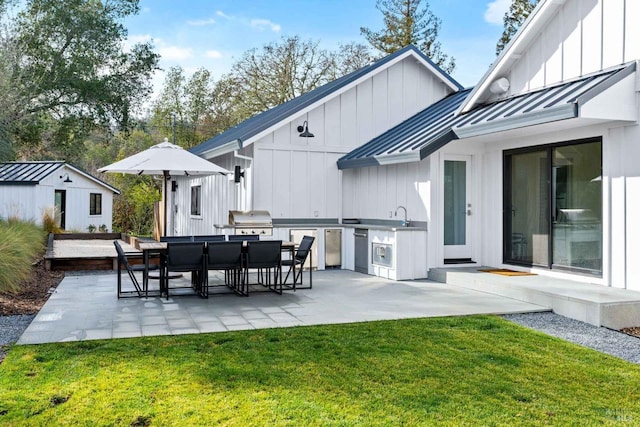 view of patio featuring exterior kitchen, outdoor dining area, a sink, an outdoor structure, and a grill