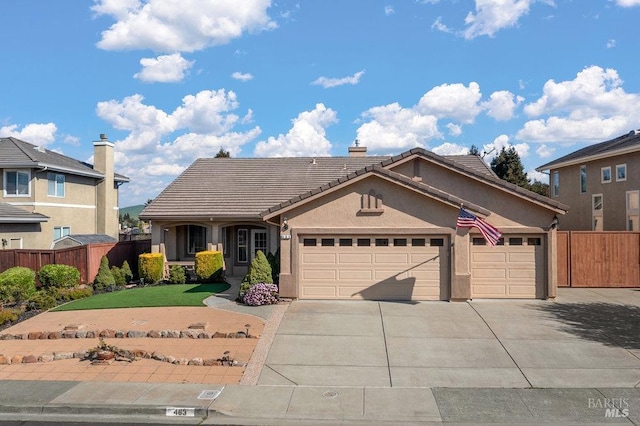 view of front of home with a tiled roof, concrete driveway, an attached garage, and fence