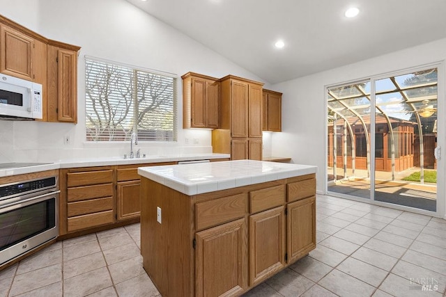 kitchen featuring tile countertops, white microwave, lofted ceiling, stainless steel oven, and black electric stovetop