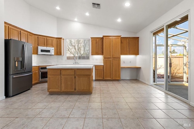 kitchen featuring light tile patterned floors, stainless steel appliances, visible vents, and brown cabinetry