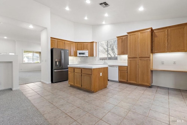 kitchen featuring white appliances, visible vents, high vaulted ceiling, light countertops, and a center island