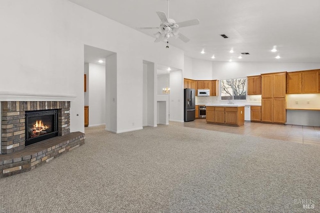 kitchen featuring white appliances, light colored carpet, a brick fireplace, and open floor plan