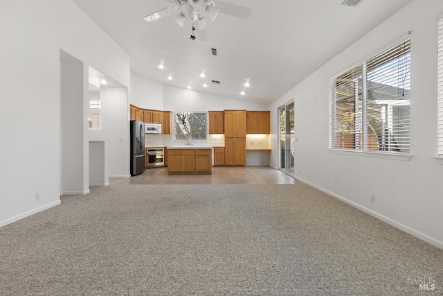 kitchen featuring white microwave, freestanding refrigerator, light colored carpet, open floor plan, and a wealth of natural light