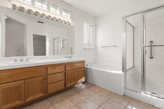 bathroom featuring tile patterned flooring, a shower stall, double vanity, a bath, and a sink