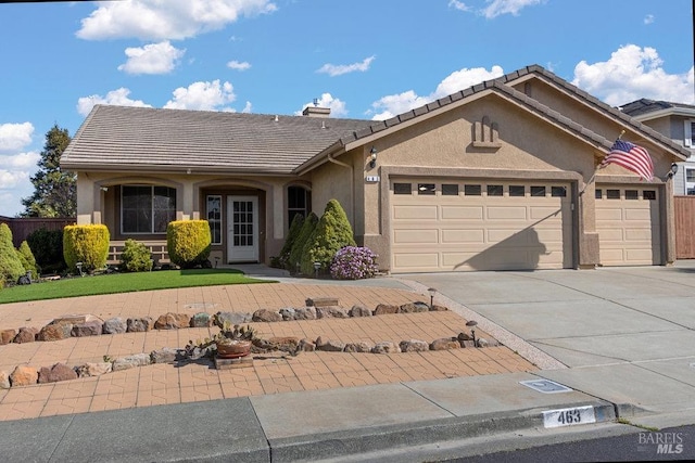 ranch-style house with stucco siding, a garage, concrete driveway, and a tiled roof