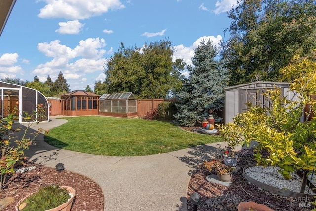 view of yard featuring a storage shed, an outbuilding, a greenhouse, and a fenced backyard