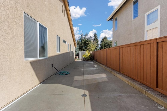 view of side of home featuring stucco siding, a patio, and fence