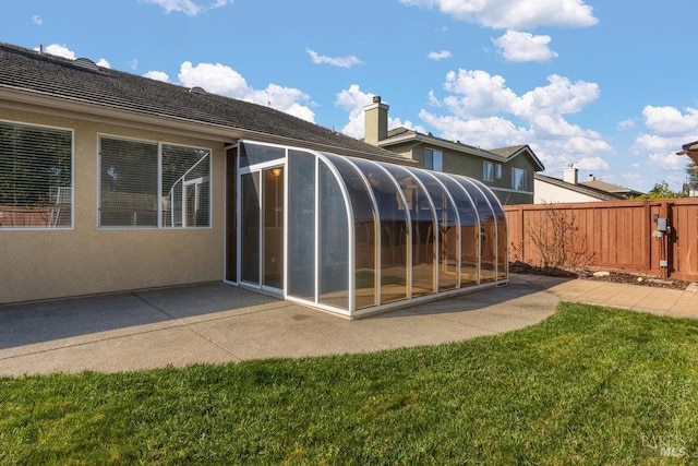 back of house featuring fence, a lawn, a sunroom, and stucco siding