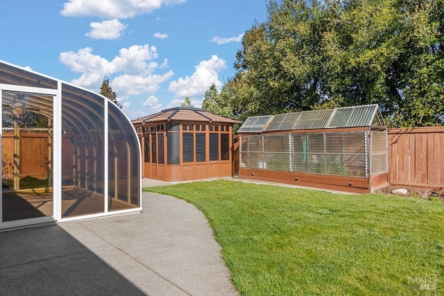 view of yard featuring a patio area, a greenhouse, an outdoor structure, and fence