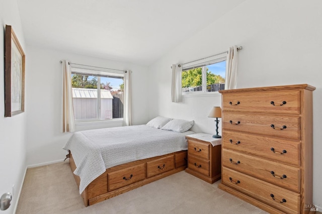 bedroom with vaulted ceiling, light colored carpet, and baseboards