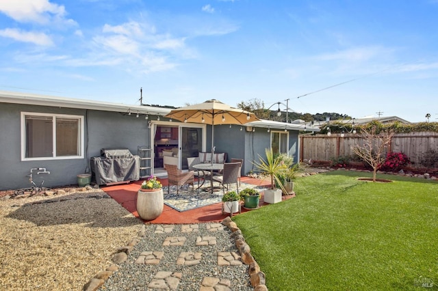 rear view of house featuring stucco siding, a patio, a yard, and fence