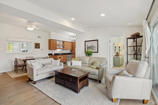 living area featuring visible vents, lofted ceiling, recessed lighting, light wood-style flooring, and ceiling fan with notable chandelier