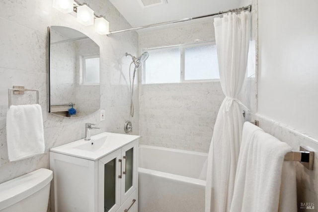 full bath with tile walls, shower / bath combination with curtain, toilet, and a healthy amount of sunlight