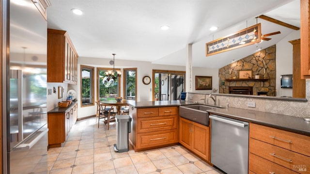 kitchen featuring brown cabinets, a sink, dark countertops, appliances with stainless steel finishes, and vaulted ceiling with beams