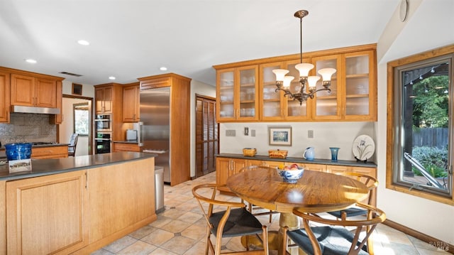 kitchen featuring dark countertops, plenty of natural light, backsplash, and under cabinet range hood