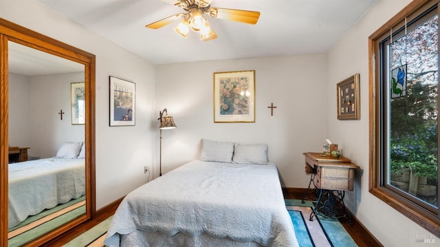 bedroom with a ceiling fan, baseboards, and wood finished floors