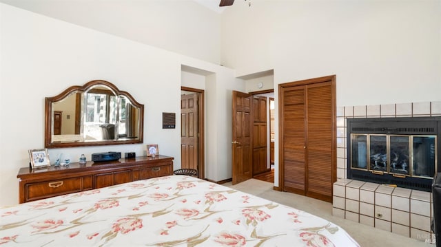 carpeted bedroom featuring a closet, a fireplace, a high ceiling, and ceiling fan