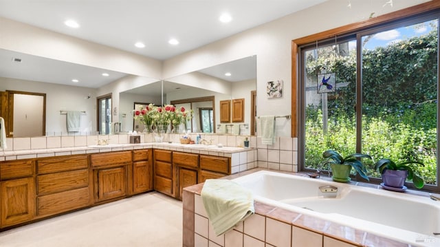 bathroom featuring double vanity, a bath, recessed lighting, and a sink