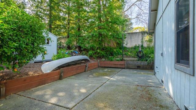 view of patio featuring an outdoor structure, a storage unit, and fence