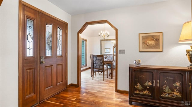 foyer featuring arched walkways, baseboards, and wood finished floors