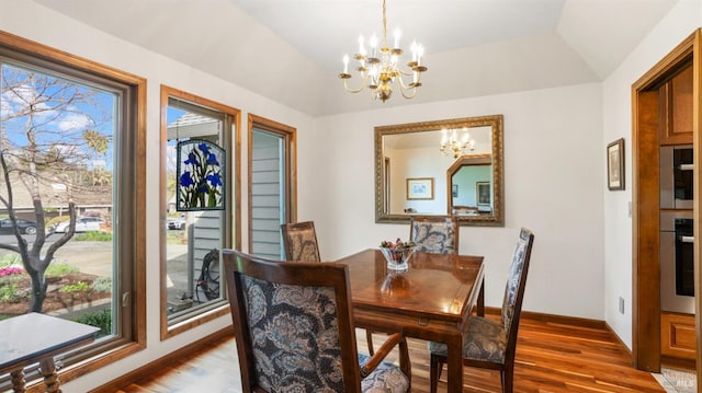 dining area featuring wood finished floors, lofted ceiling, and a chandelier