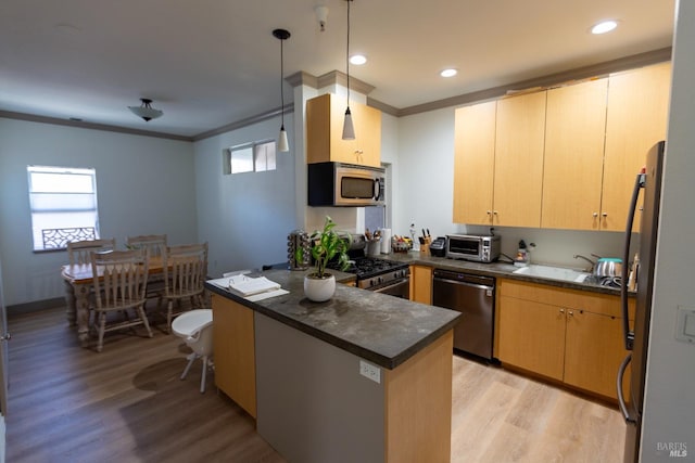 kitchen with dark countertops, a healthy amount of sunlight, a peninsula, appliances with stainless steel finishes, and crown molding