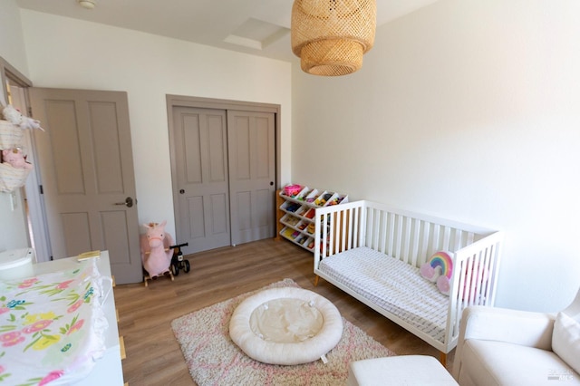 bedroom with a closet, light wood-style flooring, and a crib