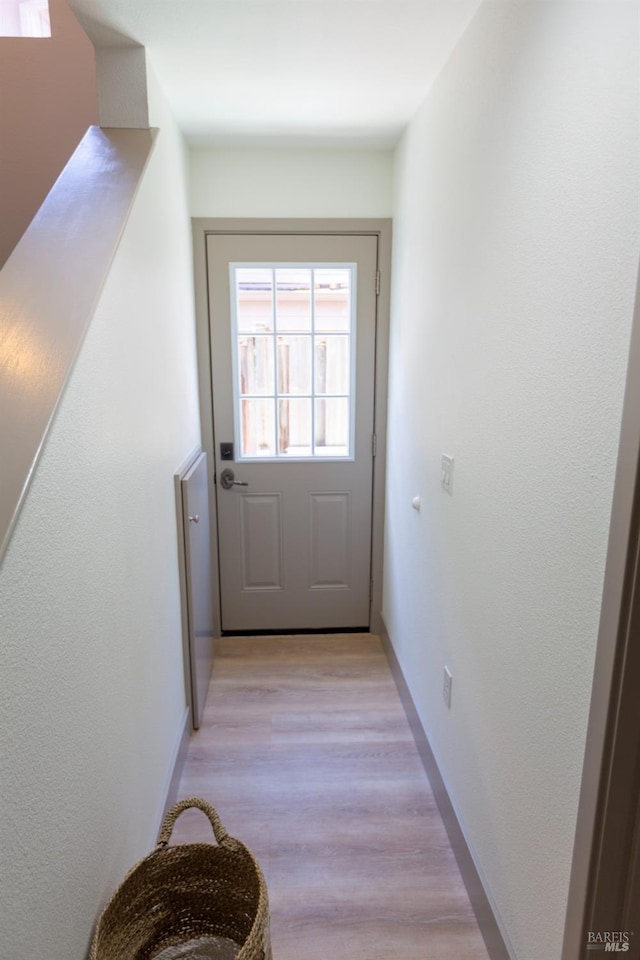 doorway to outside with light wood-style floors and baseboards