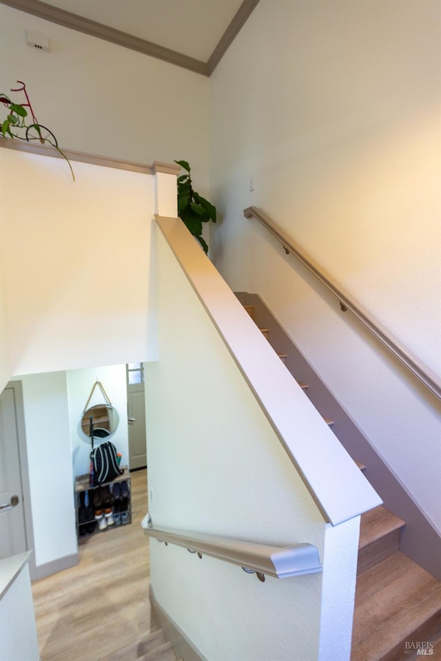 staircase with crown molding and wood finished floors