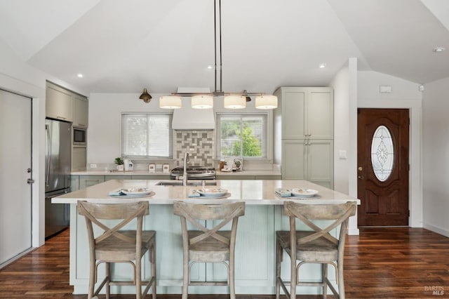 kitchen with light countertops, backsplash, appliances with stainless steel finishes, and vaulted ceiling