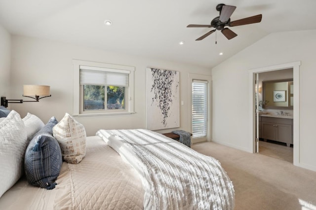 bedroom with baseboards, lofted ceiling, a sink, light carpet, and connected bathroom