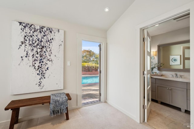 doorway featuring a sink, baseboards, light colored carpet, and recessed lighting