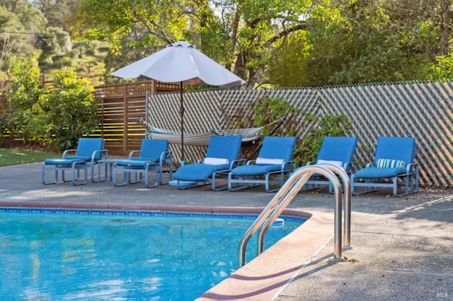 outdoor pool with a patio and fence