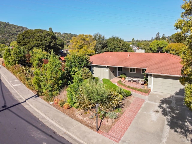 view of front of house with a tiled roof, a garage, and driveway