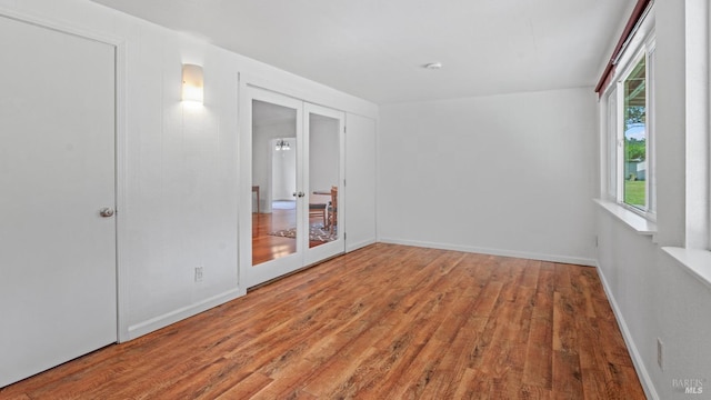 spare room with french doors, baseboards, and wood finished floors