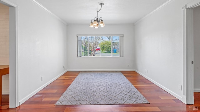 dining space featuring a chandelier, crown molding, baseboards, and wood finished floors