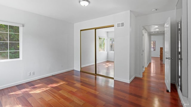 unfurnished bedroom with visible vents, baseboards, a closet, and wood finished floors