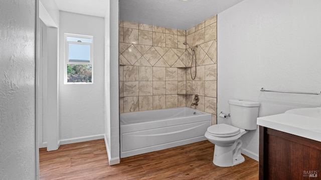 bathroom featuring toilet, wood finished floors, baseboards, bathing tub / shower combination, and vanity