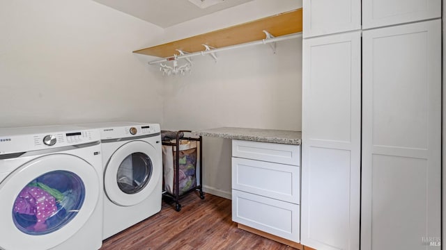 washroom featuring cabinet space, wood finished floors, and washing machine and clothes dryer