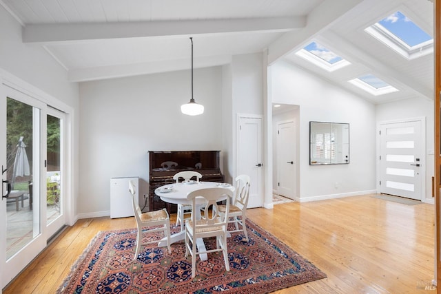 dining space with vaulted ceiling with skylight, baseboards, and light wood finished floors