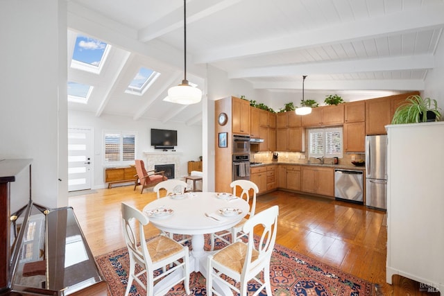 dining room with vaulted ceiling with skylight, a fireplace, and wood-type flooring