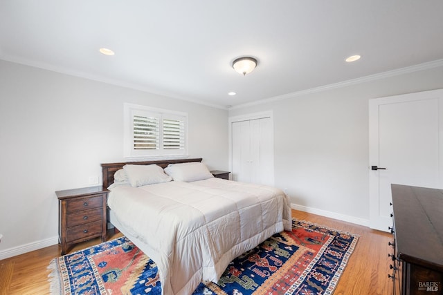 bedroom featuring light wood-type flooring, baseboards, a closet, and crown molding