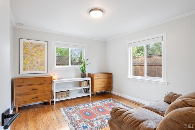 sitting room with plenty of natural light, baseboards, crown molding, and light wood-style floors