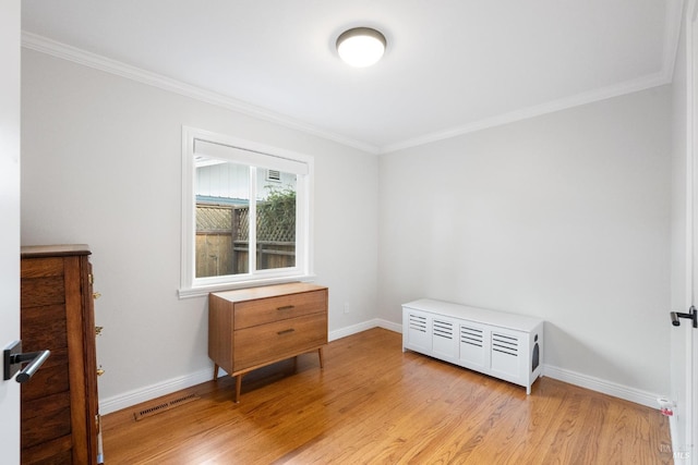 bedroom featuring baseboards, crown molding, and light wood-style floors