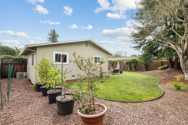 back of property featuring crawl space, central AC unit, a fenced backyard, and stucco siding