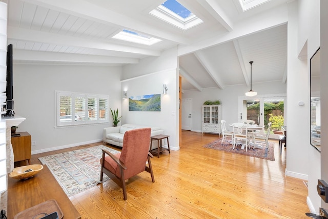 living room featuring light wood finished floors, vaulted ceiling with skylight, and baseboards